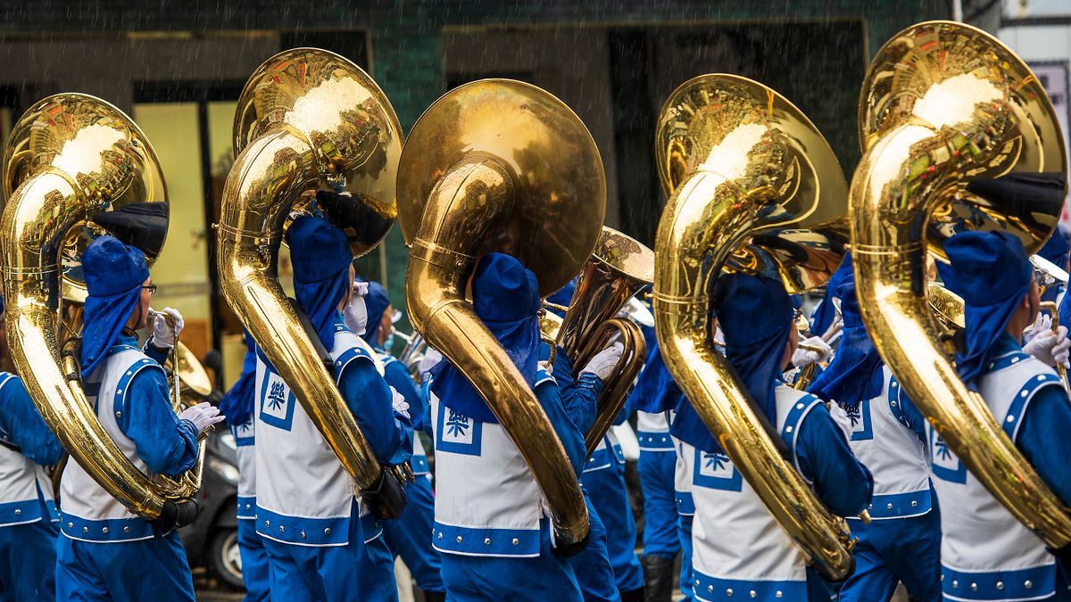 A marching band carrying brass instruments in the rain